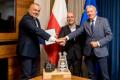 Wojciech Kamiński, Prezes Zarządu PKW S.A., Robert Kropiwnicki, Sekretarz Stanu w MAP oraz Wojciech Saługa, Marszałek Województwa Śląskiego. W tle flagi. Na stole makieta kopalni z bryłką węgla. 
