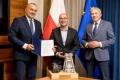 Wojciech Kamiński, Prezes Zarządu PKW S.A., Robert Kropiwnicki, Sekretarz Stanu w MAP oraz Wojciech Saługa, Marszałek Województwa Śląskiego. W tle flagi. Na stole makieta kopalni z bryłką węgla. 
