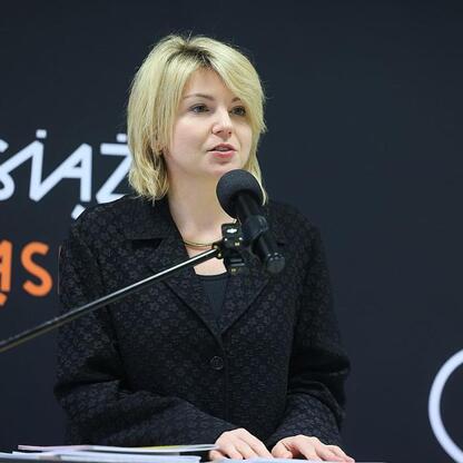 Kobieta przemawia na podium w Bibliotece Śląskiej, promując język i kulturę śląską. (wygenerowano przez AI)