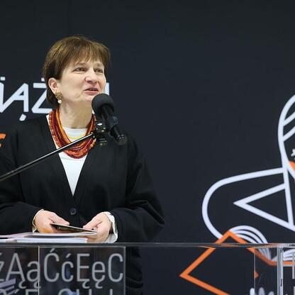 Kobieta przemawia na podium przed logo Biblioteki Śląskiej w Katowicach. (wygenerowano przez AI)