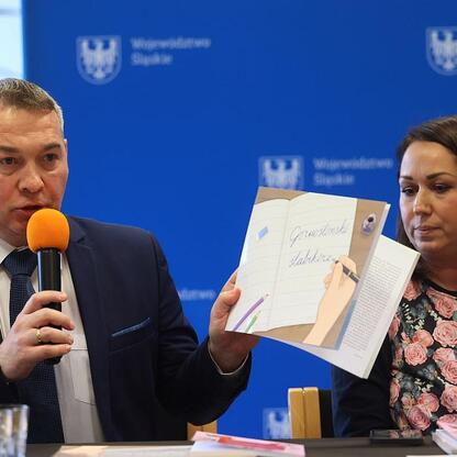 Grupa osób uczestniczy w prezentacji publikacji promujących kulturę, tradycje i język śląski w Bibliotece Śląskiej w Katowicach. (wygenerowano przez AI)