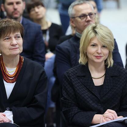 Dwie kobiety w czarnych blazerach siedzą na konferencji promującej kulturę i język śląski. (wygenerowano przez AI)