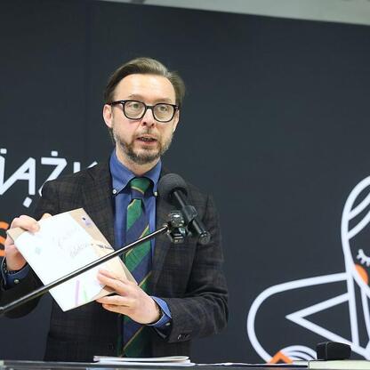Mężczyzna prezentuje publikacje na Śląskim Dniu Kultury w Katowicach. (wygenerowano przez AI)