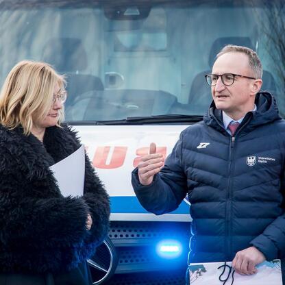 Grzegorz Boski, wicemarszałek Województwa Śląskiego, prezentuje dokument na tle ambulansu z Katowickiego Wojewódzkiego Pogotowia Ratunkowego. (wygenerowano przez AI)