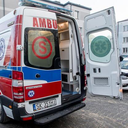 Ambulans z otwartymi drzwiami stoi na ulicy, w tle personel w zimowej odzieży. (wygenerowano przez AI)