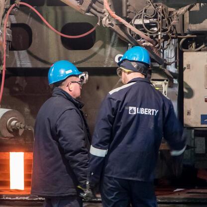 Pracownicy Huty Częstochowa w dyskusji przed maszyną produkcyjną. (wygenerowano przez AI)