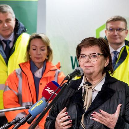 Widoczna grupa ludzi na konferencji prasowej Huty Częstochowa, z mikrofonami i w kamizelkach odblaskowych, przedstawiająca wznowienie produkcji po długim przerwie. (wygenerowano przez AI)