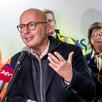 Mężczyzna przemawia na konferencji prasowej, omawiając wznowienie produkcji w Hucie Częstochowa. (wygenerowano przez AI)