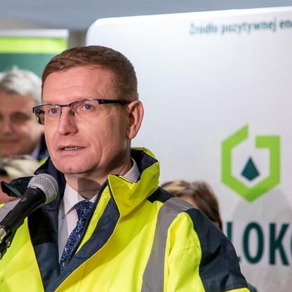 Mężczyzna w żółtym kurtku ochronnym przemawia do mediów na konferencji prasowej Huty Częstochowa. (wygenerowano przez AI)