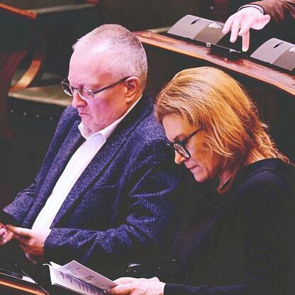 Dwóch uczestników obrad Sejmiku Województwa Śląskiego podczas pierwszej sesji roku, dyskutujących nad uchwałą ws. akcji Górnośląskiego Towarzystwa Lotniczego. (wygenerowano przez AI)