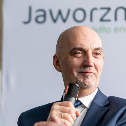 Mężczyzna w garniturze prowadzi debatę o rozwoju energetycznym Jaworzna, z mikrofonem w ręku. (wygenerowano przez AI)