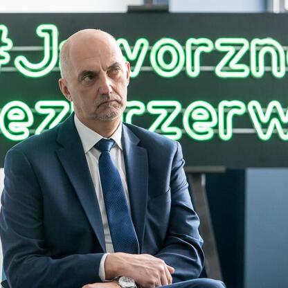 Mężczyzna w garniturze siedzi przed neonem 