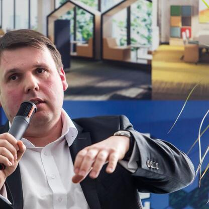 Mężczyzna w garniturze prowadzi debatę w Katowickim Laboratorium Biznesu, omawiając potencjał Jaworzno's Industrial Development Zone (JOG) i możliwości elektryfikacji przemysłu. (wygenerowano przez AI)