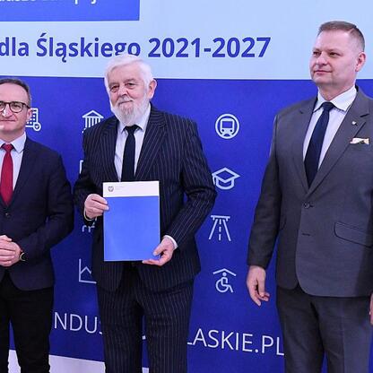 Wicemarszałek Grzegorz Boski i członek Zarządu Województwa Rafał Adamczyk wręczają listy gratulacyjne za sukcesy w projekcie Funduszu Sprawiedliwej Transformacji dla Śląska. (wygenerowano przez AI)