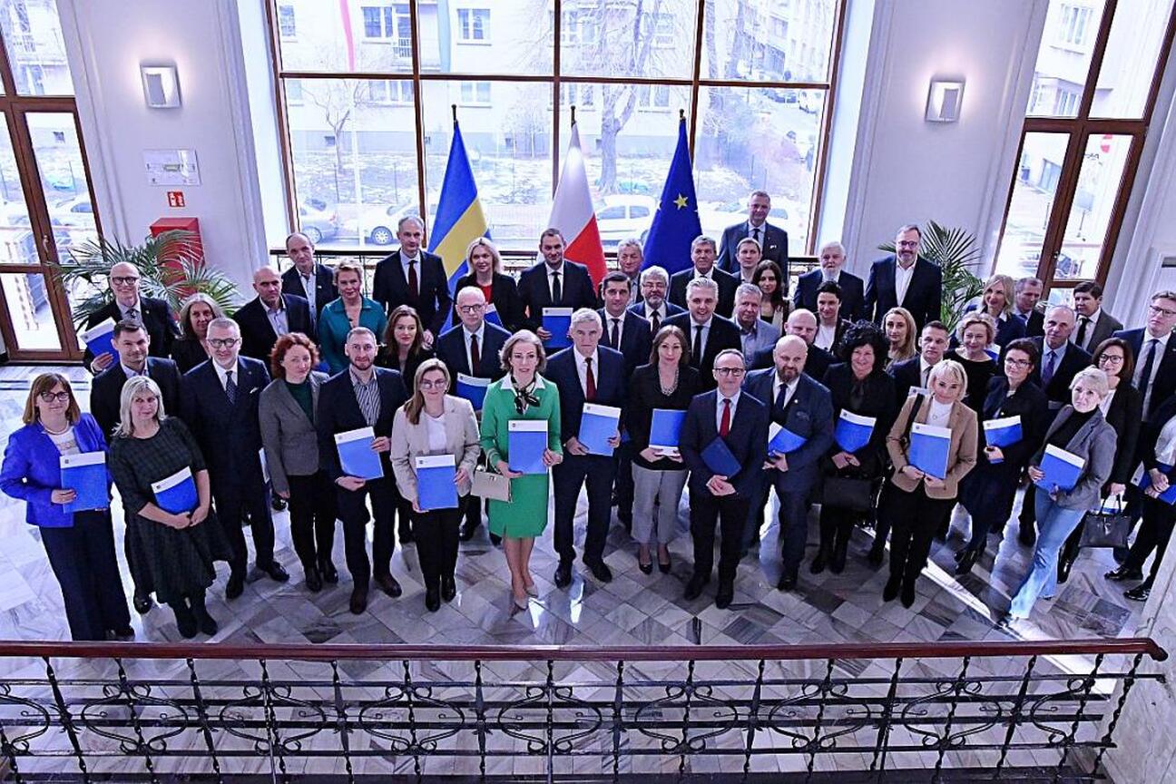 Grzegorz Boski i Rafał Adamczyk prezentują dokumenty na tle projektów odnawialnych źródeł energii w Silesia. (wygenerowano przez AI)