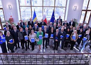 Grzegorz Boski i Rafał Adamczyk prezentują dokumenty na tle projektów odnawialnych źródeł energii w Silesia. (wygenerowano przez AI)