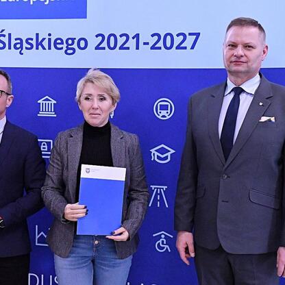 Grzegorz Boski i Rafał Adamczyk prezentują dokumenty na tle projektów odnawialnych źródeł energii w Silesia. (wygenerowano przez AI)