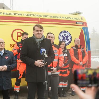 Grupa osób w mundurach stoi przed żółtym ambulansem SPZP Rejonowe Pogotowie Ratunkowe w Sosnowcu. (wygenerowano przez AI)