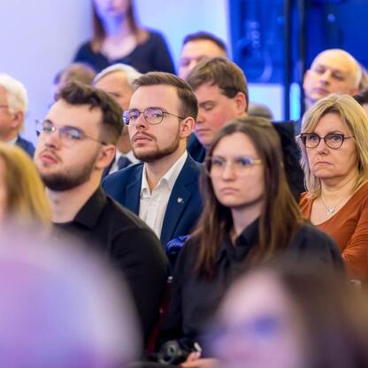 Grupa ludzi w strojach formalnych siedzi w konferencji dotyczącej projektu 