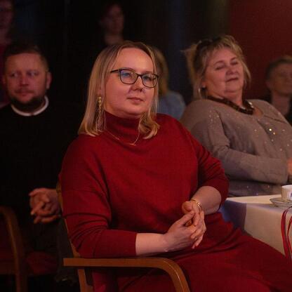 W czasie ceremonii wręczenia nagród Marszałka Województwa Śląskiego w dziedzinie kultury, uczestniczka w czerwonej sukience obserwuje uroczystość. (wygenerowano przez AI)