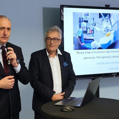 Wicemarszałek Leszek Pietraszek i dyrektor szpitala podczas konferencji z okazji 100. operacji z użyciem robota da Vinci w Katowickim Centrum Onkologii. (wygenerowano przez AI)