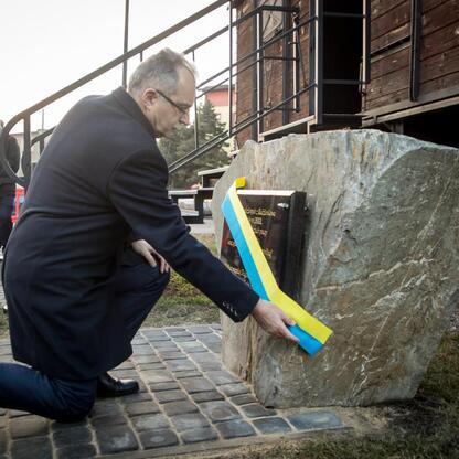 Mężczyzna kłania się przy pomniku Ofiar Tragedii Górnośląskiej, oddając hołd ofiarom deportacji. (wygenerowano przez AI)