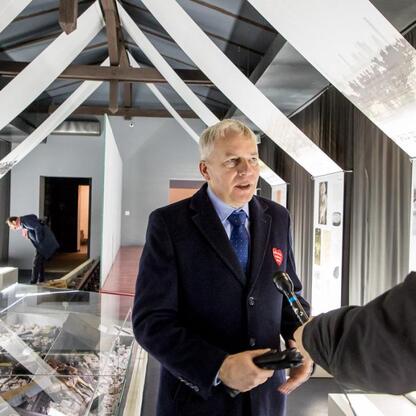 Marszałek Wojciech Saługa w rozmowie z dziennikarzem w muzeum upamiętniającym Tragedię Górnośląską. (wygenerowano przez AI)
