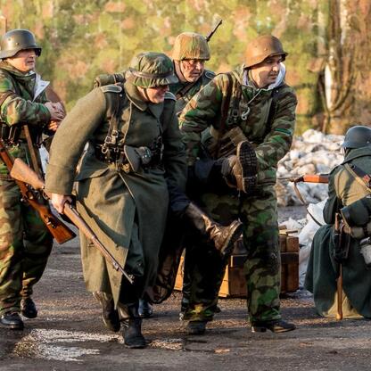 Grupa żołnierzy w mundurach wojskowych uczestniczy w rekonstrukcji wydarzeń z 1945 roku, związanych z Tragedią Górnośląską. (wygenerowano przez AI)