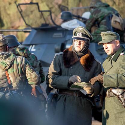 Zdjęcie przedstawia grupę w mundurach wojskowych, uczestniczącą w rekonstrukcji wydarzeń związanych z Tragedią Górnośląską. (wygenerowano przez AI)