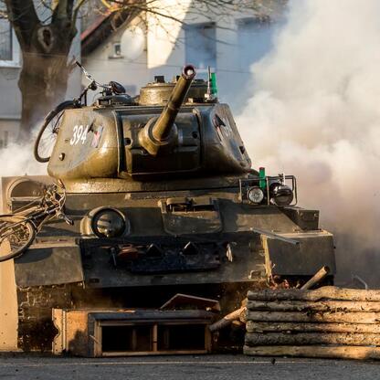 Tank z dymem i rowerem na dachu, symbolizujący rekonstrukcję historyczną. (wygenerowano przez AI)
