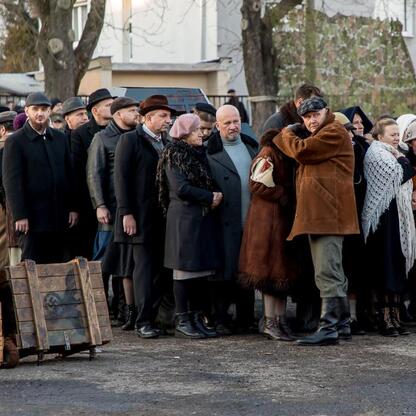 Grupa ludzi w strojach z okresu połowy XX wieku, uczestniczących w rekonstrukcji historycznej, w ramach obchodów 80. rocznicy Tragedii Górnośląskiej. (wygenerowano przez AI)