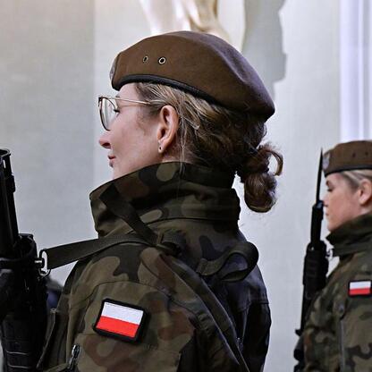 Wojownik w mundurze wojskowym z flagą Polski i karabinem, stojący przed pomnikiem, uczestniczący w uroczystościach 80. rocznicy Tragedii Górnośląskiej. (wygenerowano przez AI)