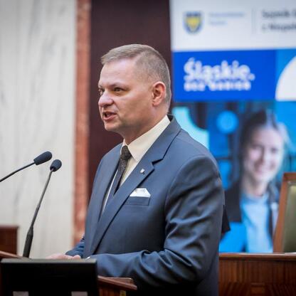 Rafał Adamczyk, członek Zarządu Województwa Śląskiego, przemawia na sesji Sejmiku Osób z Niepełnosprawnością Województwa Śląskiego. (wygenerowano przez AI)