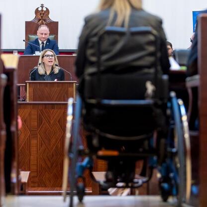 Monika Sikora przemawia na sesji Sejmiku Osób z Niepełnosprawnością Województwa Śląskiego. (wygenerowano przez AI)