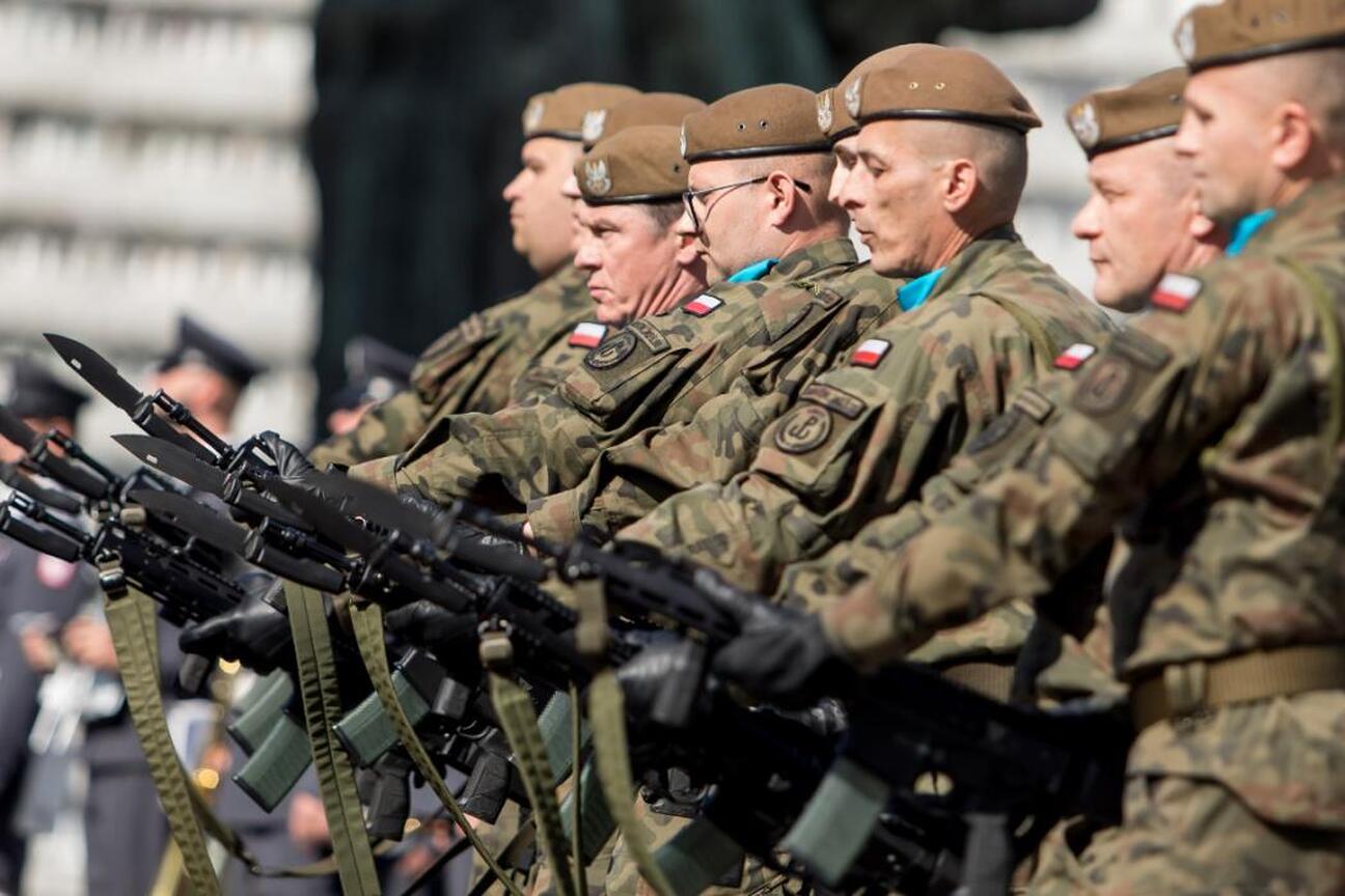 Zdjęcie przedstawia żołnierzy w mundurach wojskowych marszujących w formacji, trzymając karabiny. (wygenerowano przez AI)