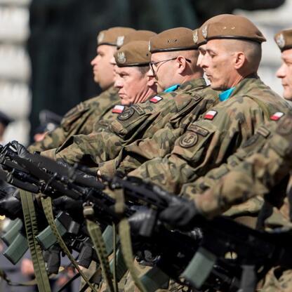 Zdjęcie przedstawia żołnierzy w mundurach wojskowych marszujących w formacji, trzymając karabiny. (wygenerowano przez AI)