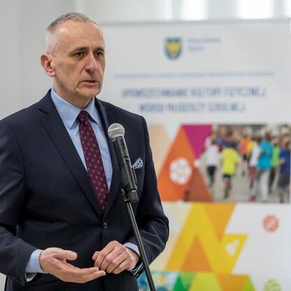 Wicemarszałek Leszek Pietraszek przemawia na podium podczas uroczystości podsumowującej wyniki sportowych zawodów szkół w Katowicach. (wygenerowano przez AI)