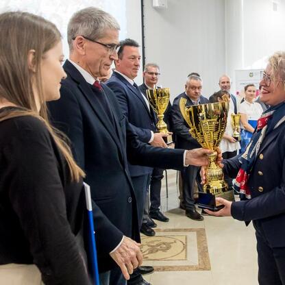 Podczas uroczystości wręczenia nagród w Silesia School Sports Federation, uczestnicy i oficjalni przedstawiciele uczestniczą w ceremonii wręczenia trofeum. (wygenerowano przez AI)