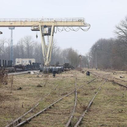 Abandoned industrial site with overgrown tracks and rusted gantry crane, former coal mining area in Gliwice, Poland. (wygenerowano przez AI)