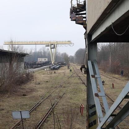 Przemysłowe przekształcenie terenu w Gliwicach, gdzie dawni robotnicy przemysłu ciężkiego stają się nowymi pracownikami kolejowymi. (wygenerowano przez AI)