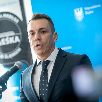 Wicemarszałek Województwa Śląskiego Grzegorz Boski prezentuje ofertę Kolei Śląskich na konferencji prasowej. (wygenerowano przez AI)