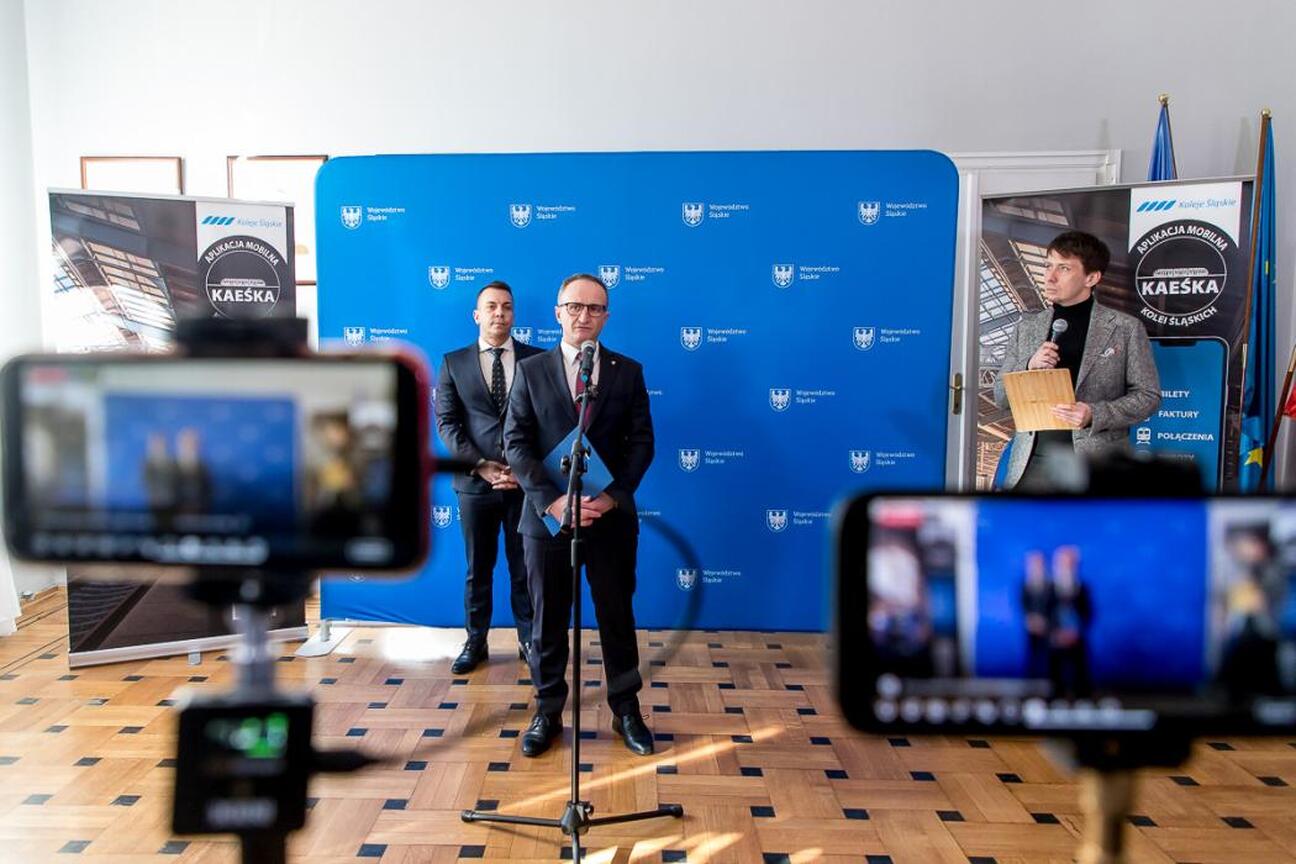 Wicemarszałek Województwa Śląskiego Grzegorz Boski i wiceprezes Kolei Śląskich Tomasz Niedziela prezentują nową ofertę dla dzieci i młodzieży podczas konferencji prasowej. (wygenerowano przez AI)