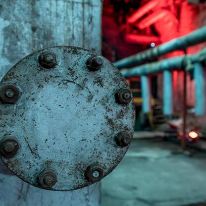 Metaliczna flanga przemysłowa z widocznymi śladami zużycia, ustawiona w ciemnym, czerwono-świecącym środowisku przemysłowym. (wygenerowano przez AI)