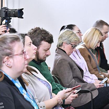 Siedzący ludzie uczestniczą w briefingu w Silesia Voivodeship Marshal's Office, omawiając pierwszy w Polsce plan adaptacji do zmian klimatu. (wygenerowano przez AI)