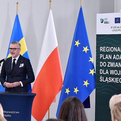 Formalna sesja w Urzędzie Marszałkowskim Śląska, gdzie Rafał Adamczyk prezentuje plan adaptacji do zmian klimatu. (wygenerowano przez AI)