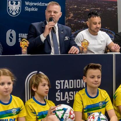 Członek Zarządu Województwa Śląskiego, Rafał Adamczyk, przemawia na konferencji prasowej w Stadionie Śląskim, przedstawiając Ronaldinho Show. (wygenerowano przez AI)