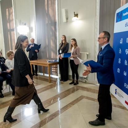 Wicemarszałek Grzegorz Boski wręcza gratulacje na konferencji o funduszy europejskich dla Śląska 2021-2027. (wygenerowano przez AI)