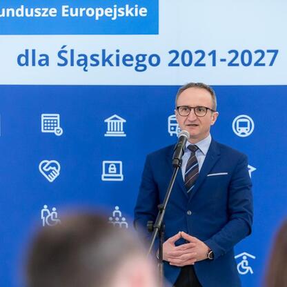 Grzegorz Boski, Wicemarszałek Województwa Śląskiego, przemawia na podium o funduszach europejskich dla Śląska 2021-2027. (wygenerowano przez AI)