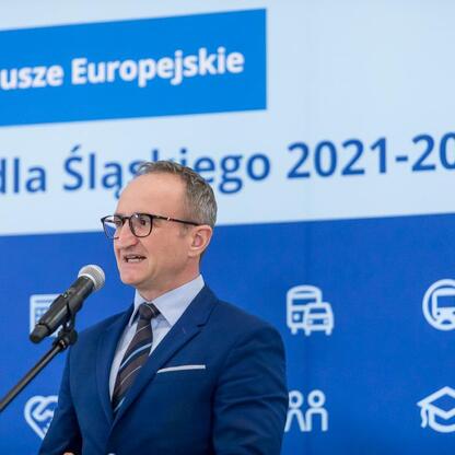 Wicemarszałek Grzegorz Boski przemawia na podium o fundusze europejskie dla Śląska 2021-2027. (wygenerowano przez AI)