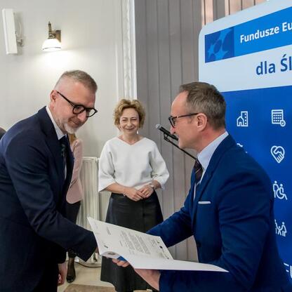 Grzegorz Boski wręcza gratulacje przedstawicielom gmin w ramach programu Fundusze Europejskie dla Śląska 2021-2027. (wygenerowano przez AI)